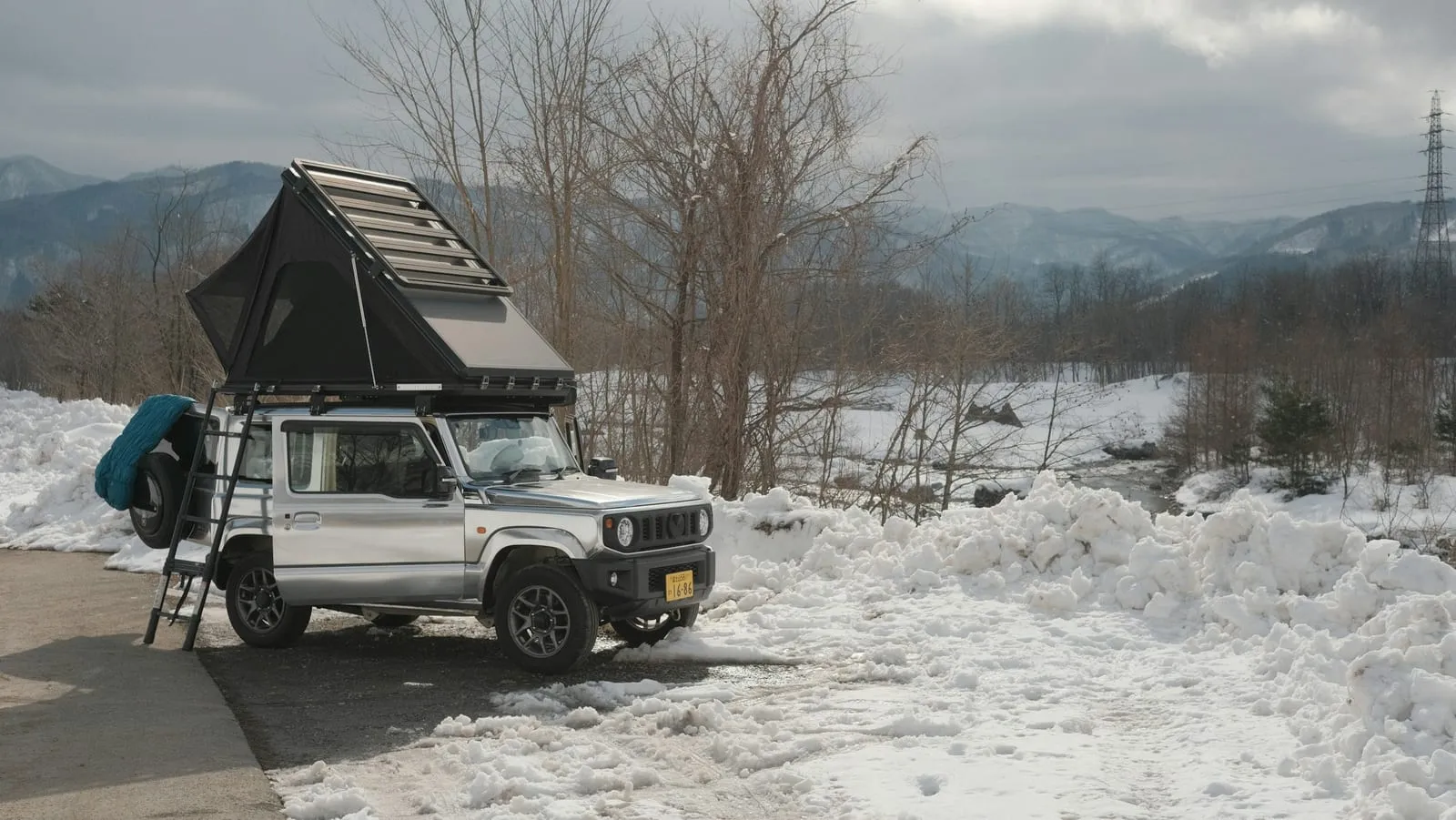 a jeep with a tent on top of it parked in the snow