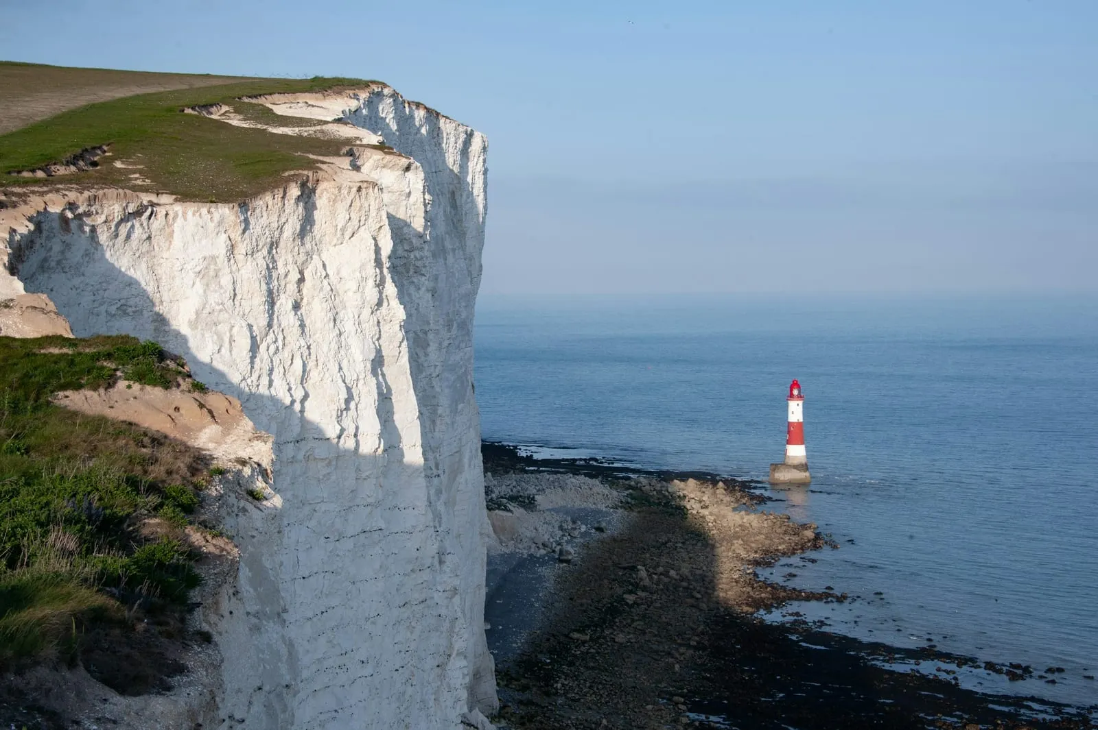 White cliffs and a lighthouse overlook the sea.
